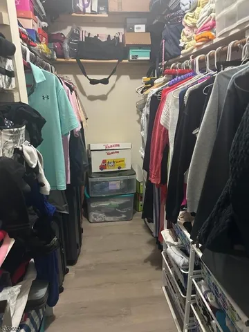 a view of walk in closet with clothes and shoes