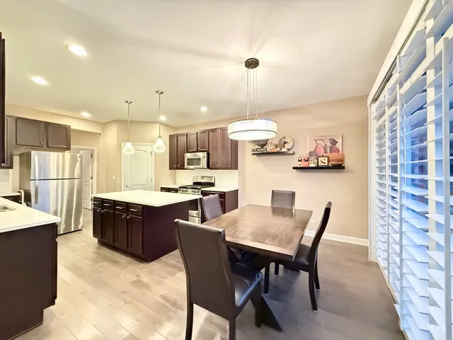 a kitchen with a dining table chairs and refrigerator