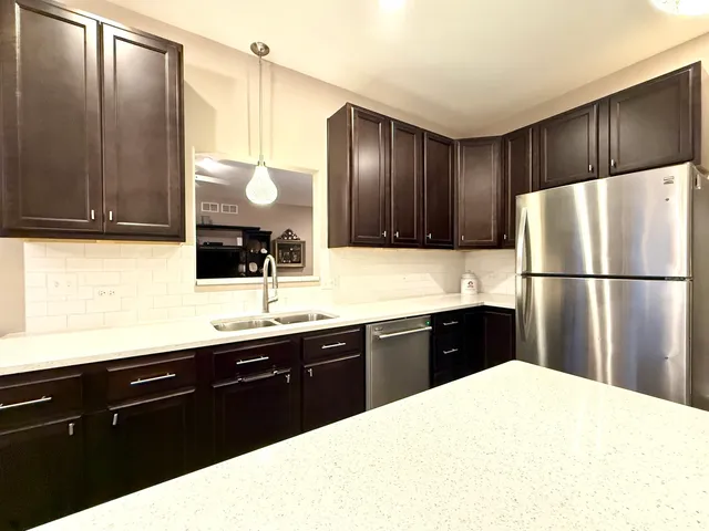 a kitchen with a sink a refrigerator and wooden cabinets