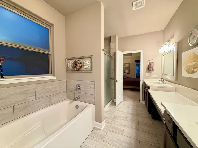 a bathroom with a tub a sink and a large mirror