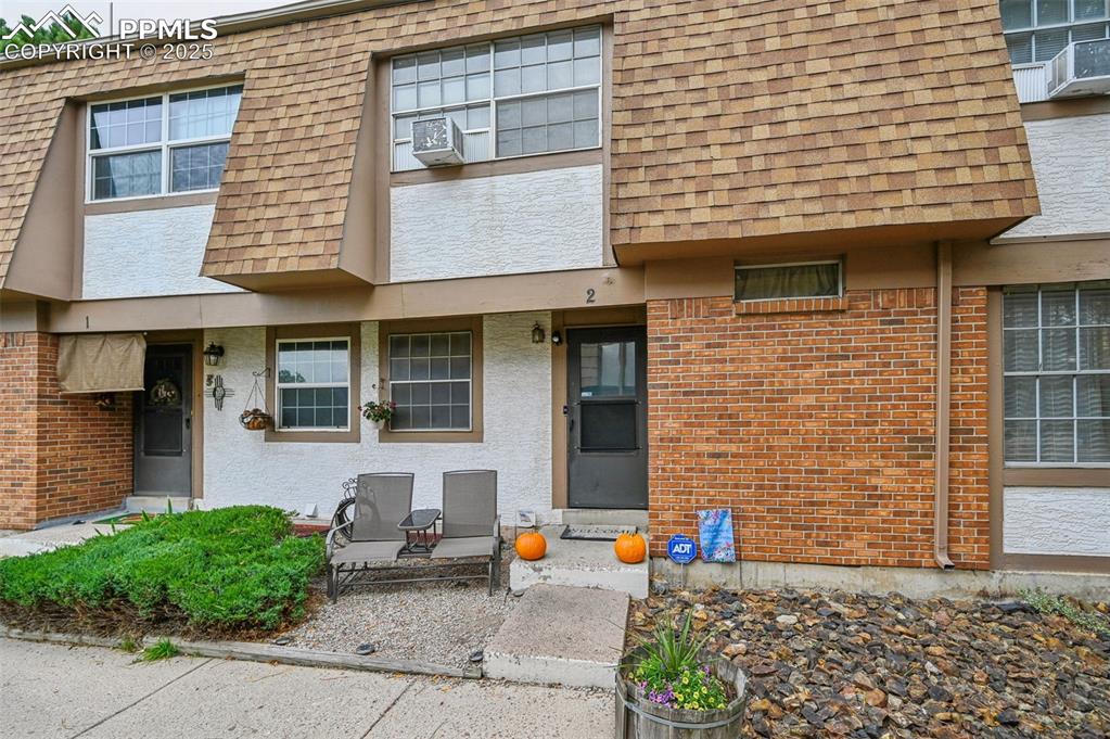 1131 Willow Bend Circle, Unit 2 Colorado Springs, CO 80918 - Photo 2 of 21 a view of a brick house with large windows and plants