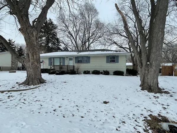 a front view of a house with a yard covered in snow