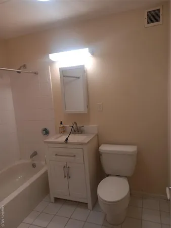 a bathroom with a toilet sink vanity tub and mirror