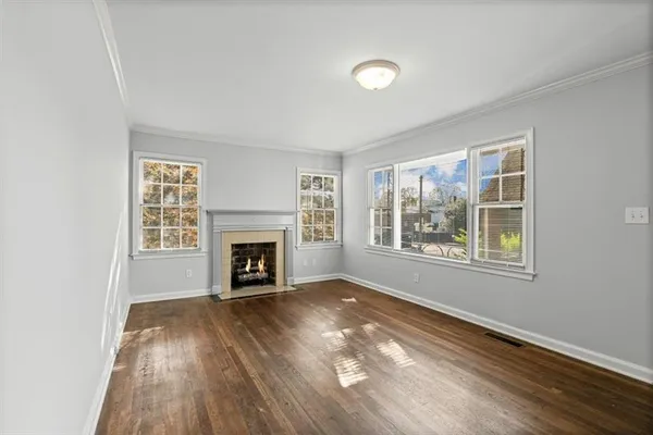 a view of an empty room with wooden floor fireplace and a window