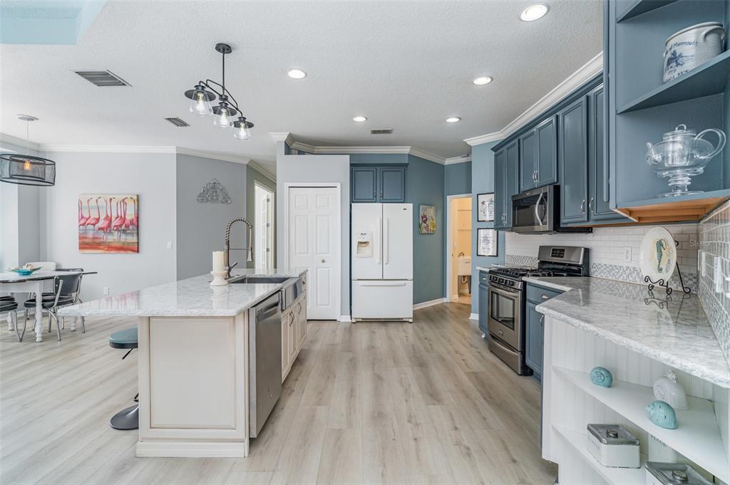 302 Latitude Place Apollo Beach, FL 33572 - Photo 12 of 50 a kitchen with stainless steel appliances granite countertop a refrigerator a stove top oven a sink dishwasher and white cabinets with wooden floor