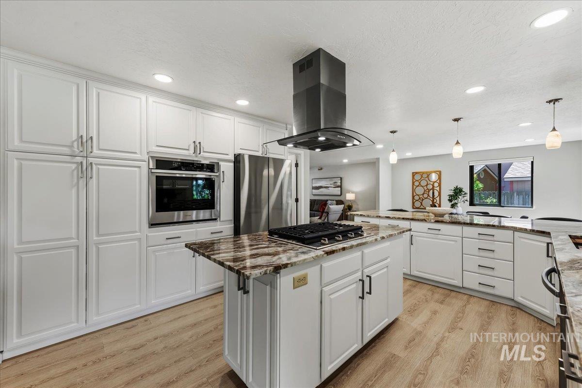 599 Pebble Beach Way Eagle, ID 83616 - Photo 12 of 44 Spacious kitchen featuring an expansive island with a gas cooktop, sleek stainless steel range hood, and integrated double wall oven