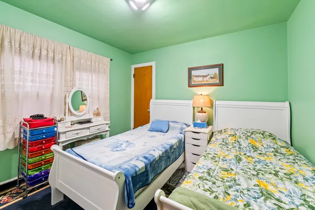 a bedroom with a bed and a dresser next to a window