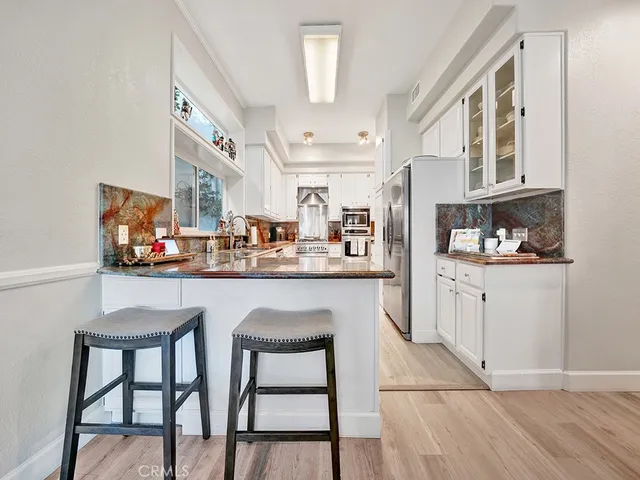 a kitchen with stainless steel appliances kitchen island granite countertop a table chairs sink and cabinets