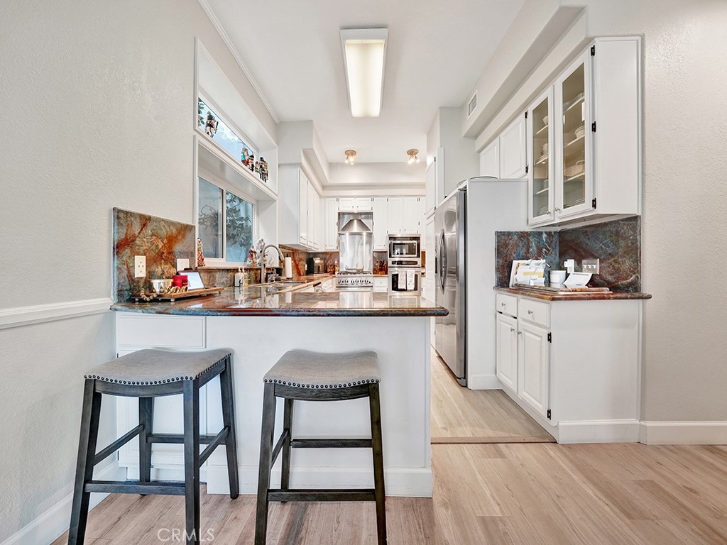 34102 Crystal Lantern Dana Point, CA 92629 - Photo 13 of 43 a kitchen with stainless steel appliances kitchen island granite countertop a table chairs sink and cabinets