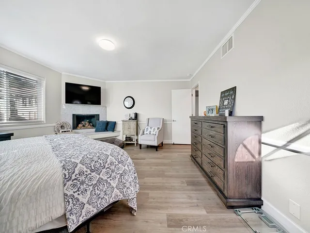 a bedroom with a bed a mirror and a flat tv screen on dresser
