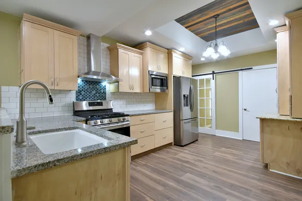 a kitchen with stainless steel appliances granite countertop a refrigerator a sink and white cabinets