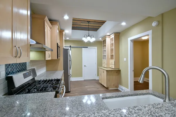 a large kitchen with a refrigerator a sink dishwasher a stove and white cabinets with wooden floor