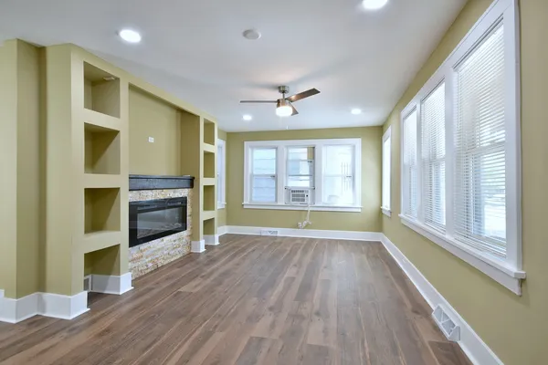 a view of a livingroom with wooden floor a ceiling fan and a window