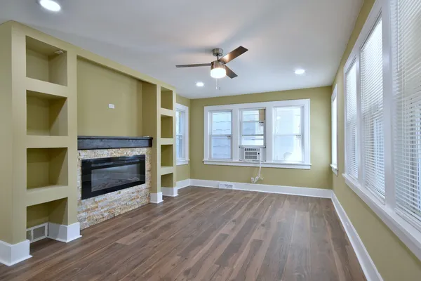 a view of an empty room with wooden floor fireplace and a window