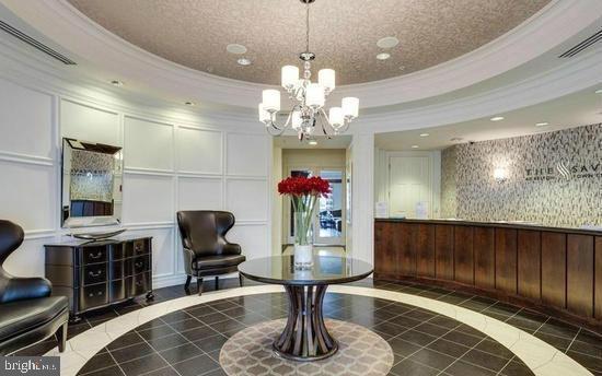 12000 Market Street, Unit 445 Reston, VA 20190 - Photo 2 of 4 a living room with couches chandelier and a view of kitchen appliances