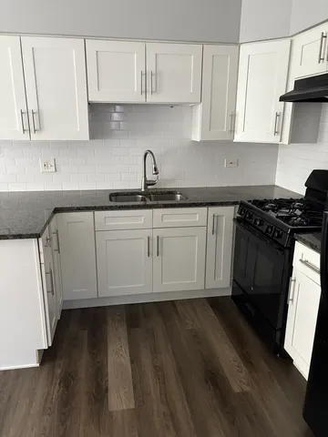 a kitchen with granite countertop white cabinets and a stove top oven