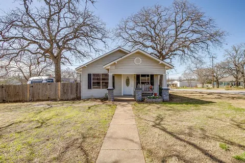 a front view of a house with a yard and trees
