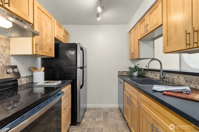 a kitchen with stainless steel appliances granite countertop a sink stove and refrigerator