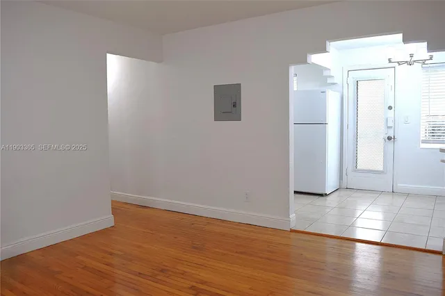 an empty room with wooden floor and fan