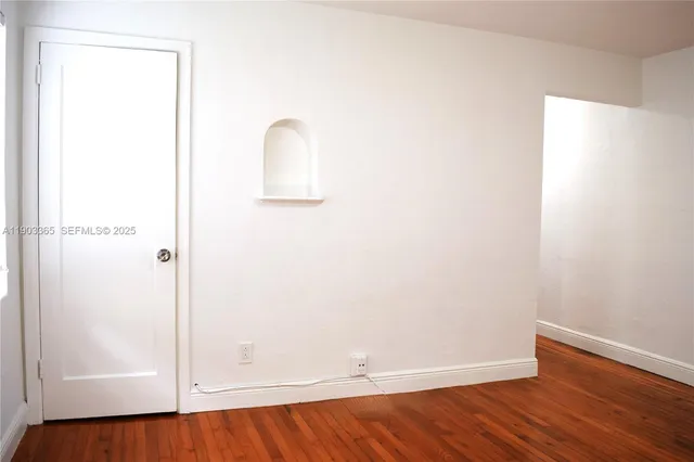 an empty room with wooden floor and window