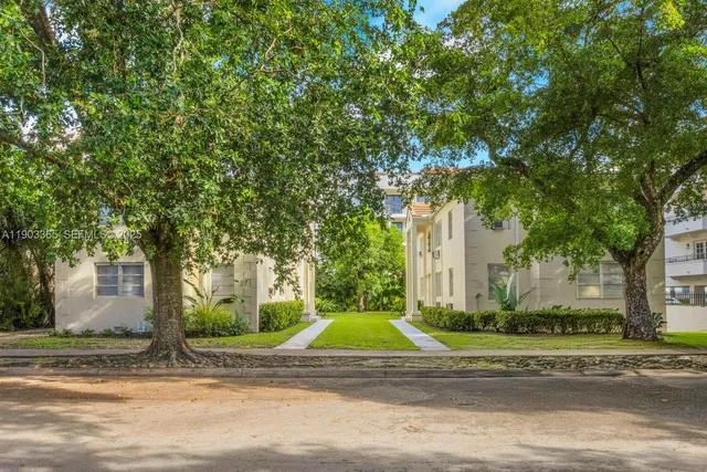a view of a house with a small yard and a large tree