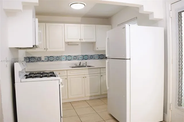 a kitchen with a refrigerator a stove a sink and cabinets