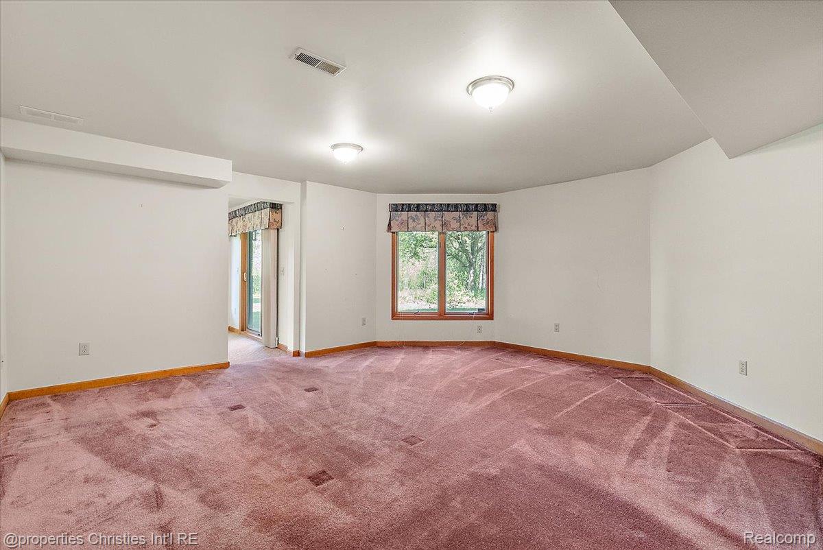 6175 Tripp Road Holly, MI 48442 - Photo 27 of 63 Spacious room featuring ample natural light from multiple windows, wall-to-wall carpeting, white painted walls, and ceiling-mounted lighting fixtures