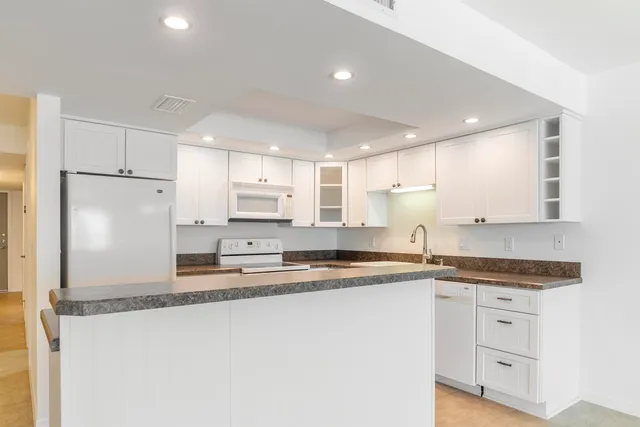 a kitchen with stainless steel appliances granite countertop a sink refrigerator and cabinets