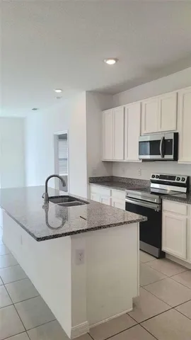 a kitchen with kitchen island granite countertop a stove a sink and a counter top space