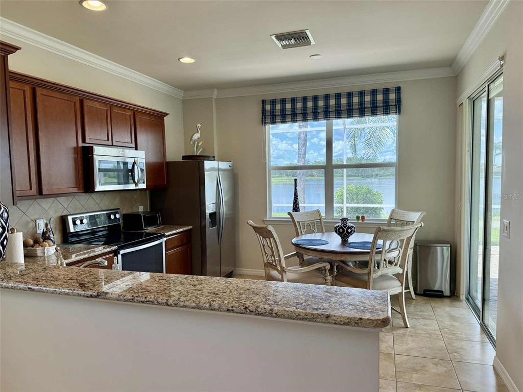 19240 Isadora Street Venice, FL 34293 - Photo 11 of 41 a dining room with stainless steel appliances granite countertop a sink dishwasher a stove and a refrigerator with wooden floor