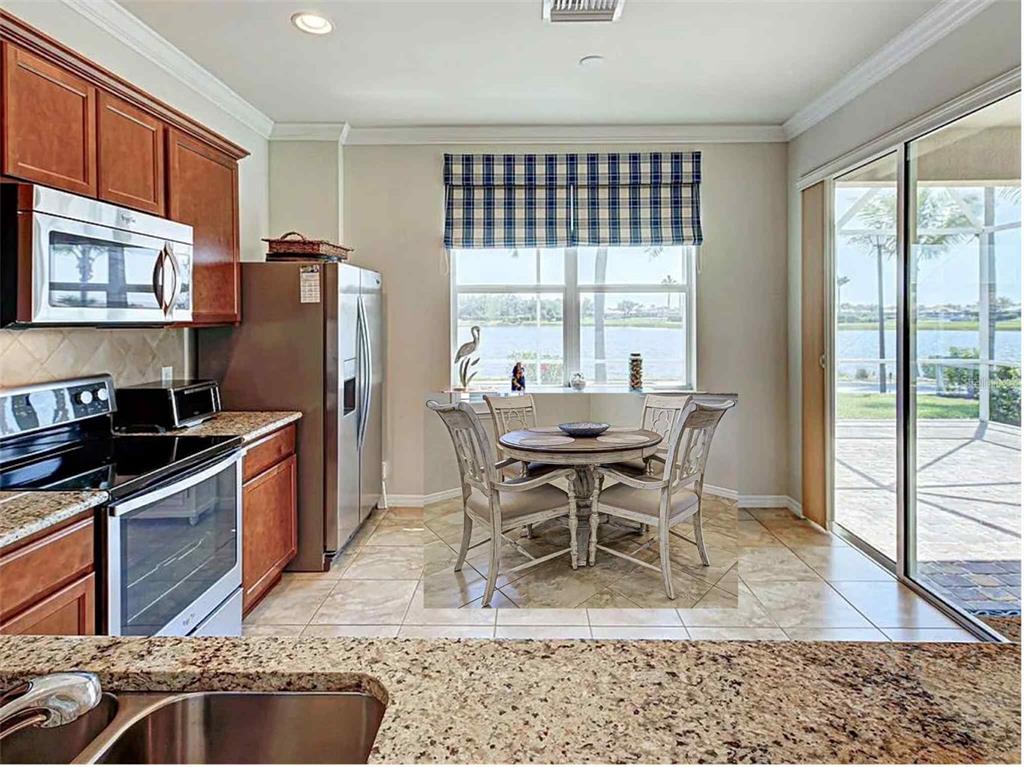 19240 Isadora Street Venice, FL 34293 - Photo 12 of 41 a kitchen with stainless steel appliances granite countertop a stove a refrigerator a sink a dining table and chairs with wooden floor