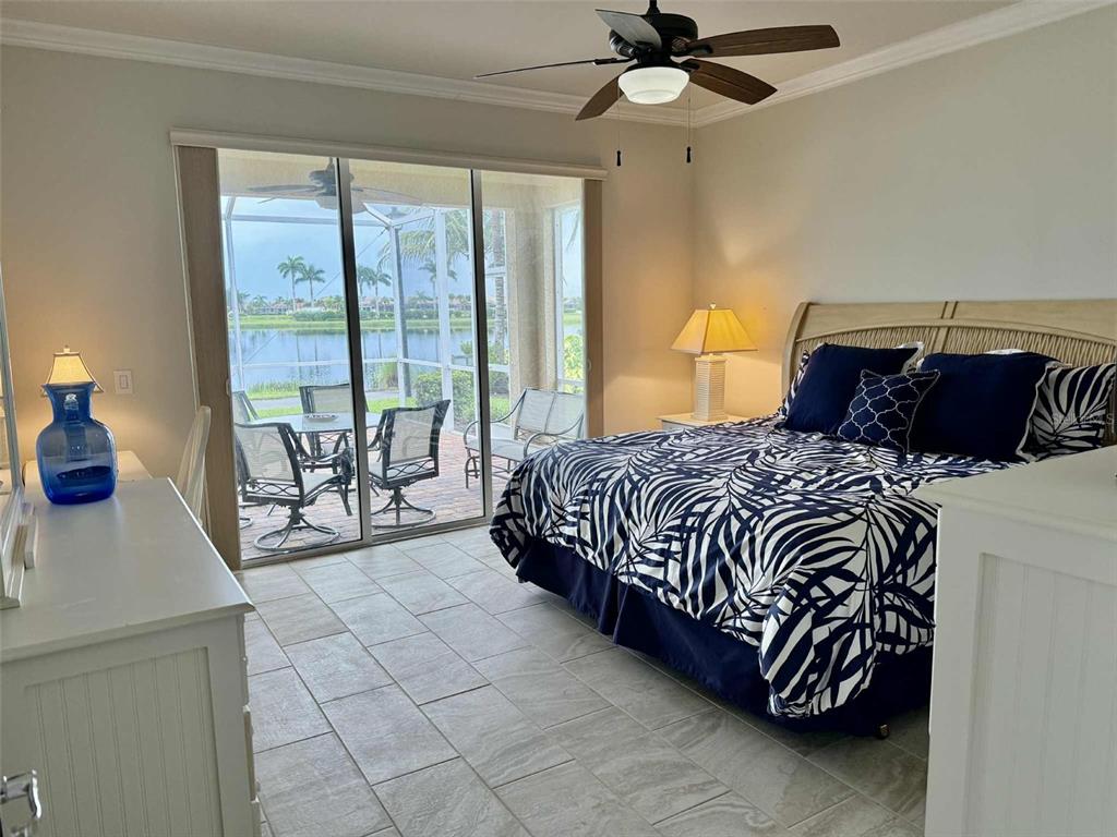 19240 Isadora Street Venice, FL 34293 - Photo 16 of 41 a bedroom with a large bed and a chandelier fan