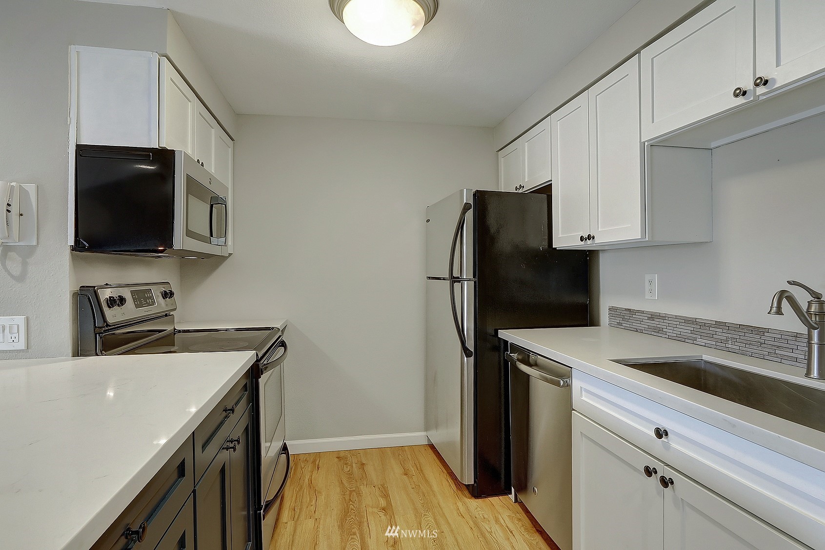 1124 North 92nd Street, Unit 101 Seattle, WA 98103 - Photo 5 of 14 a kitchen with a sink a refrigerator and cabinets