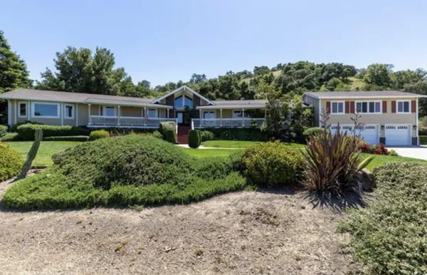 a front view of a house with a yard and potted plants