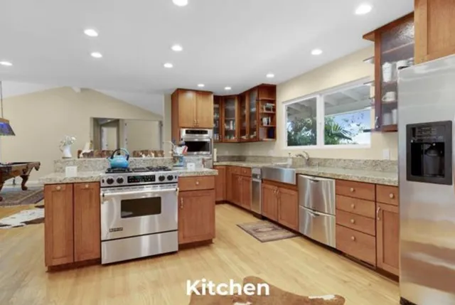 a kitchen with stainless steel appliances granite countertop a stove a sink and a refrigerator