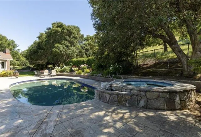 a view of swimming pool with sitting area in backyard