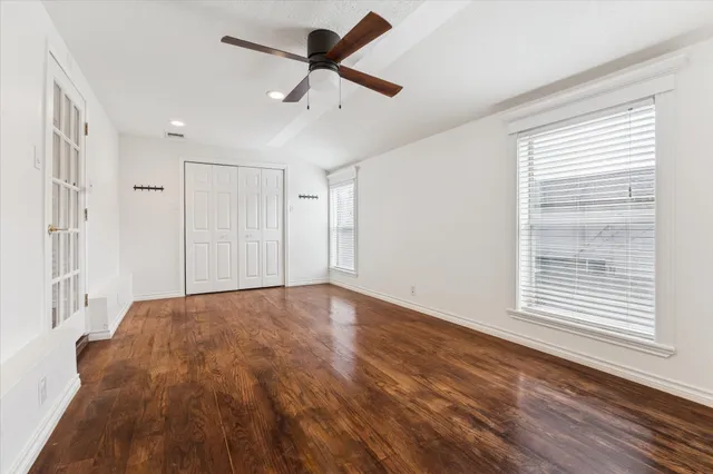 a view of empty room with wooden floor and fan
