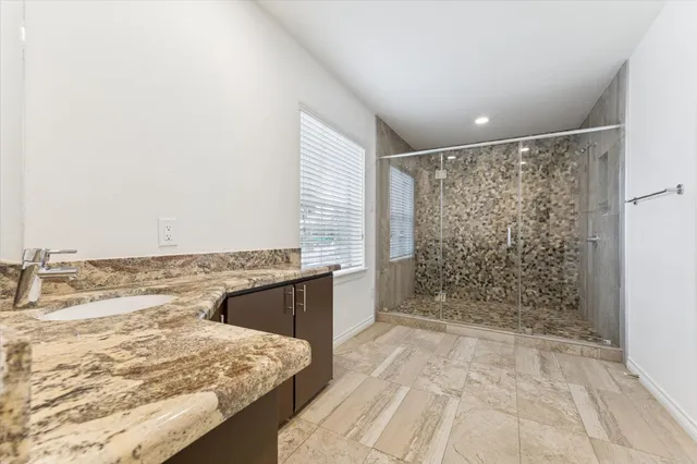 a bathroom with a granite countertop sink a shower and a bathtub