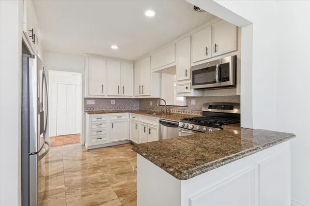 a kitchen with stainless steel appliances granite countertop a stove sink and cabinets