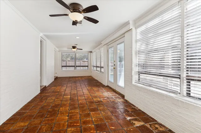 a big room with wooden floor a chandelier fan and windows