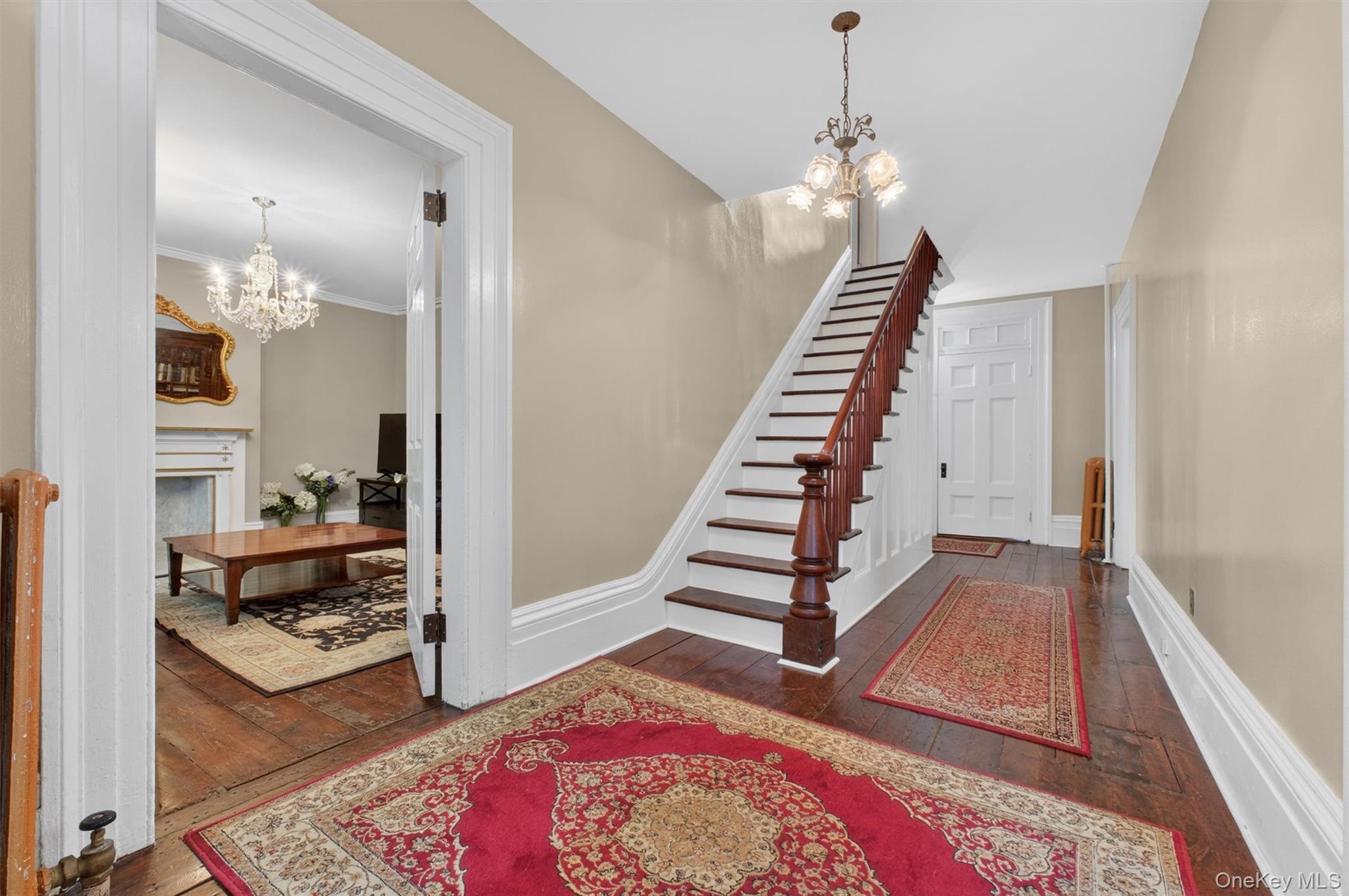 121 Old Glenham Road Fishkill, NY 12524 - Photo 5 of 50 Foyer showcasing hardwood flooring, a classic chandelier, a dark wood staircase with balusters, hallway and door leading to a living area.