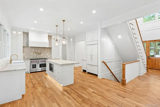 a large kitchen with stainless steel appliances kitchen island granite countertop a stove a sink a refrigerator and a wooden floors