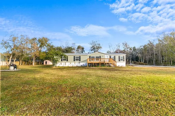 a view of a house with a big yard and large trees