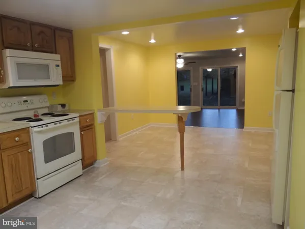 a view of a hallway with stainless steel appliances granite countertop cabinets and wooden floor