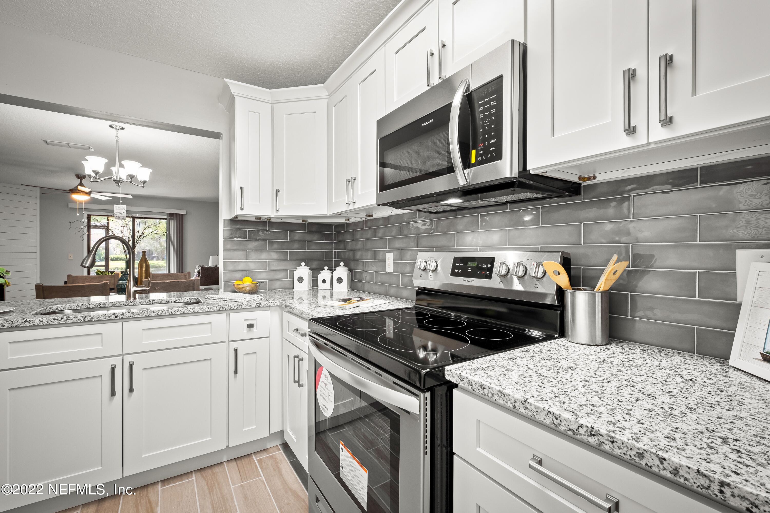 a kitchen with stainless steel appliances granite countertop a sink stove and white cabinets