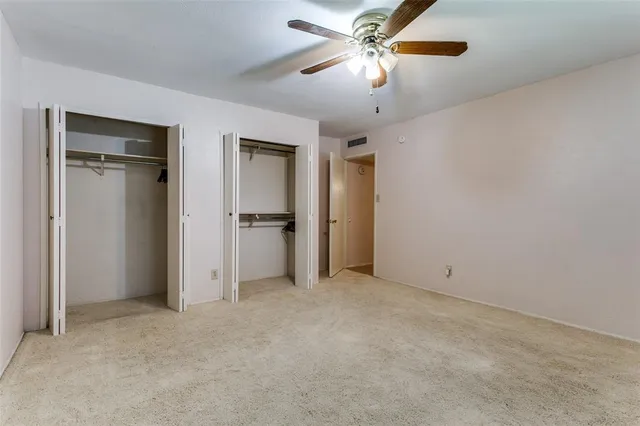 an empty room with closet and a ceiling fan