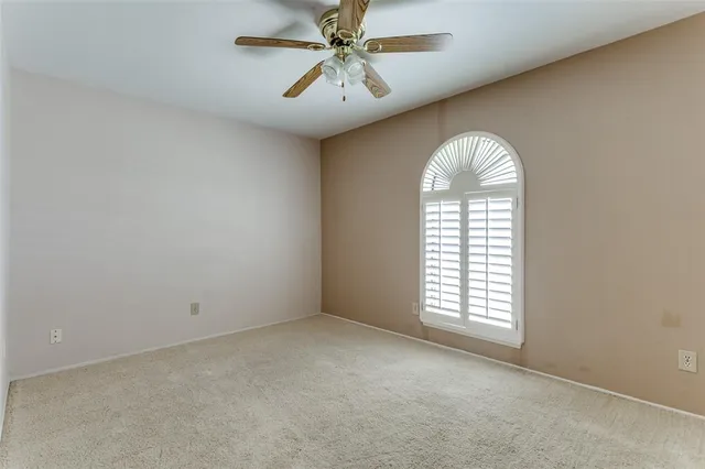 an empty room with windows and ceiling fan view