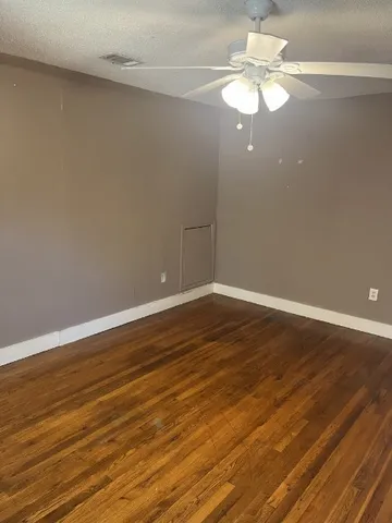 a view of a room with wooden floor and ceiling fan