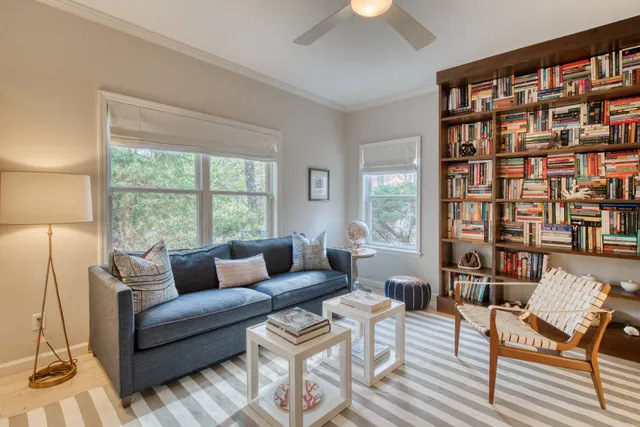 a living room with furniture and a large window with bookshelf