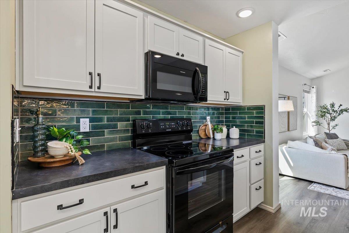 12781 Ashfield Street Caldwell, ID 83607 - Photo 28 of 30 Kitchen with black appliances, dark countertops, white cabinetry, open floor plan, and dark wood finished floors